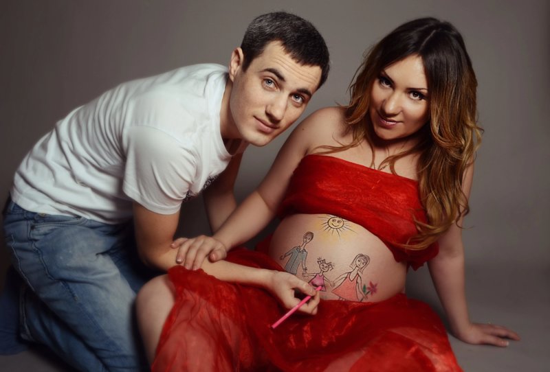Муж рисует на животе беременной жены